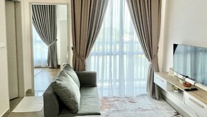 A modern living room with a sofa, a flat-screen TV, and a large window with curtains. - Plaza Kelana Jaya by Sleepy Bear (Petaling Jaya)
