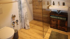 A modern bathroom with a glass shower enclosure, a toilet, a sink, and a vanity with a mirror.