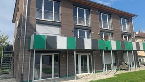 A multi-story building with balconies, large windows, and a covered entrance area.