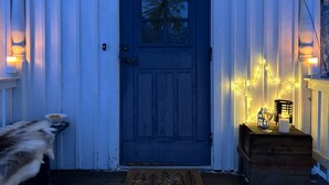A blue door with a window, a small dog, and a wooden crate with a candle and a glass.
