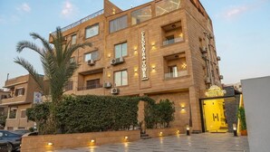 A multi-story hotel with a prominent entrance, large windows, and a well-lit facade. - Cleopatra Tower Pyramids Hotel (Giza)