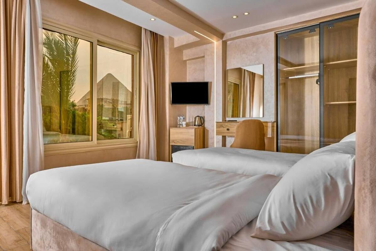 Quarto de hotel com cama grande, televisão, guarda-roupa e vista para palmeiras.