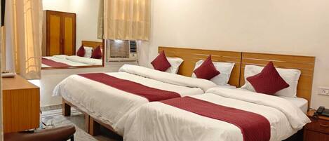 A hotel room with a large bed, a desk, a chair, and a mirror.