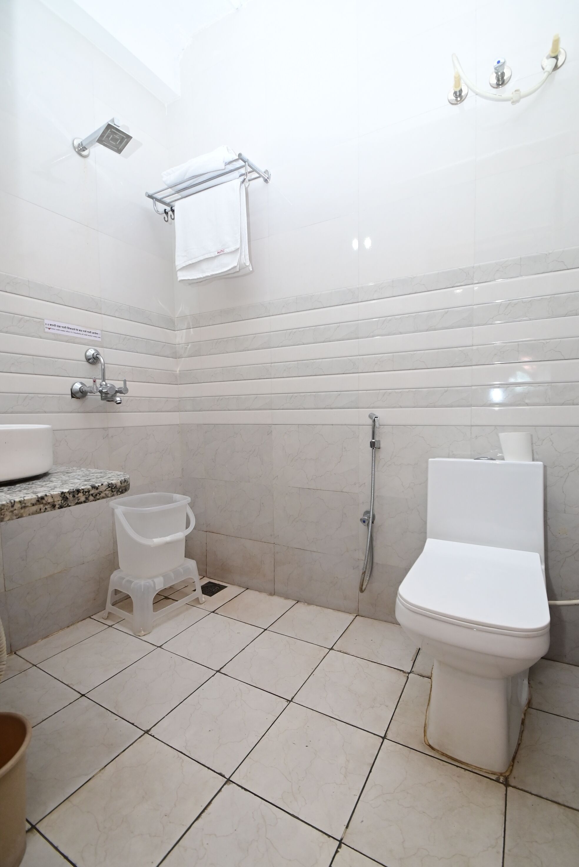 A bathroom with a toilet, bidet, sink, and a towel rack.