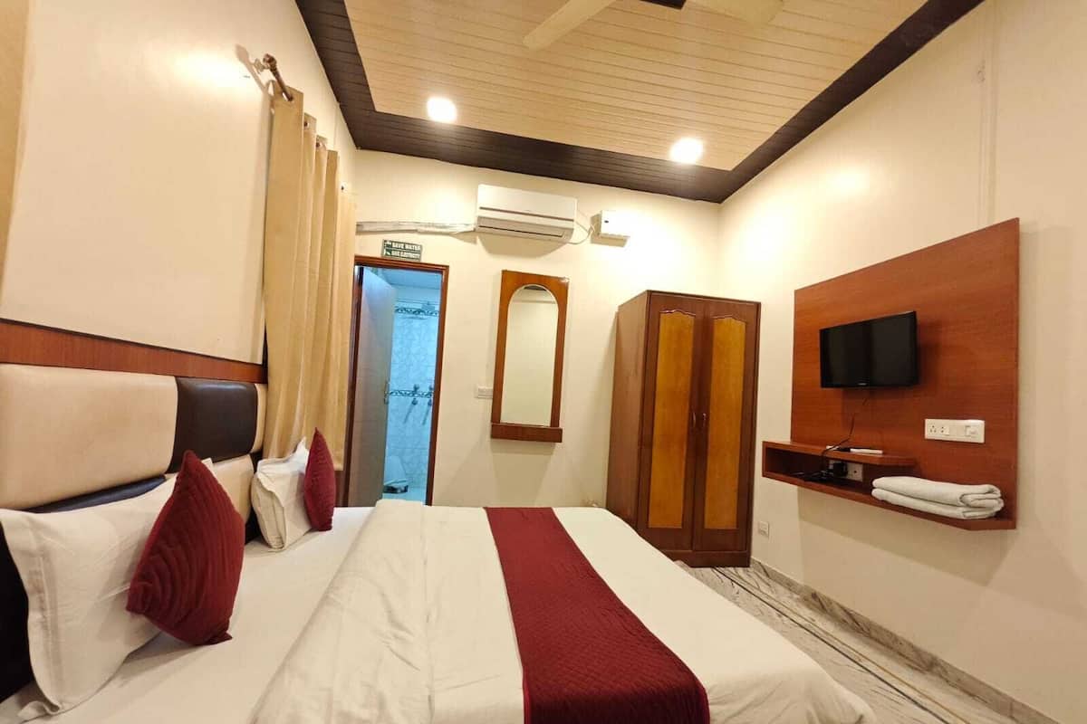 Una habitación de hotel con cama, televisión, armario y aire acondicionado.