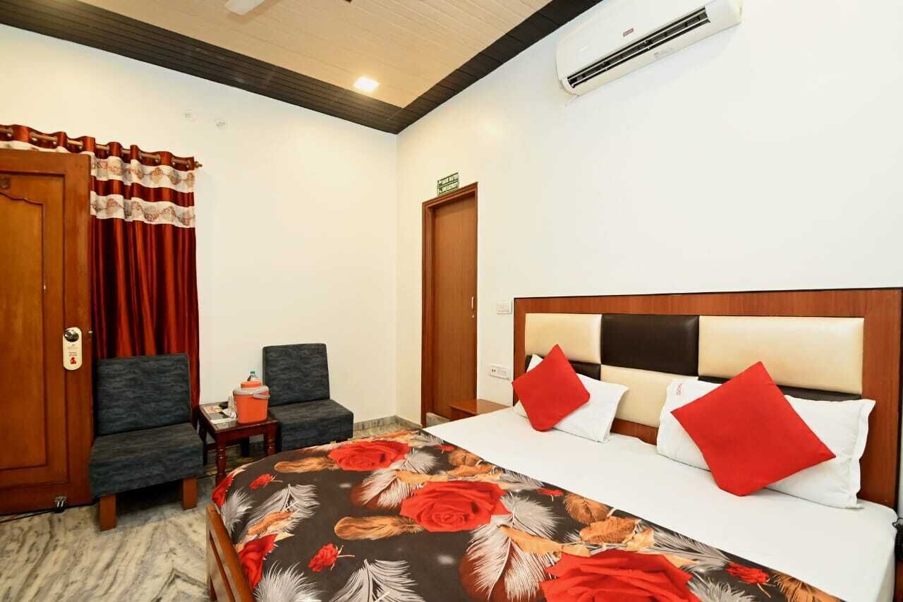 Una habitación de hotel con una cama, una silla, una mesita y un equipo de aire acondicionado.