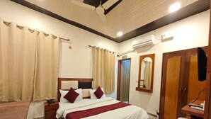 Una habitación de hotel con cama, escritorio, espejo, armario y aire acondicionado.