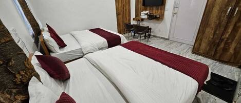 A hotel room with two beds, a TV mounted on the wall, and a wooden wardrobe.