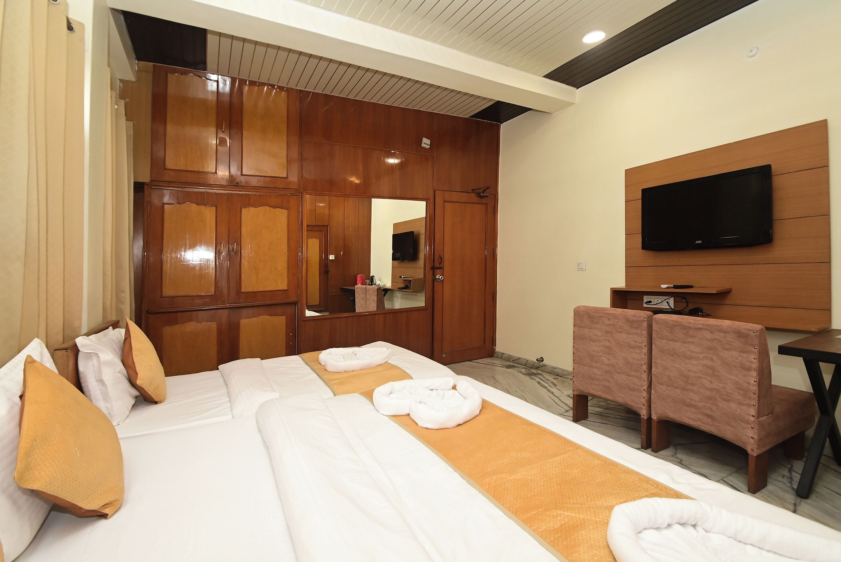 A hotel room with a bed, a TV, a wardrobe, and a seating area.