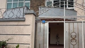 A two-story building with a gated entrance, a small garden area, and a visible staircase leading to the upper floor. - UNIQUE GUEST HOUSE (Addis Ababa)