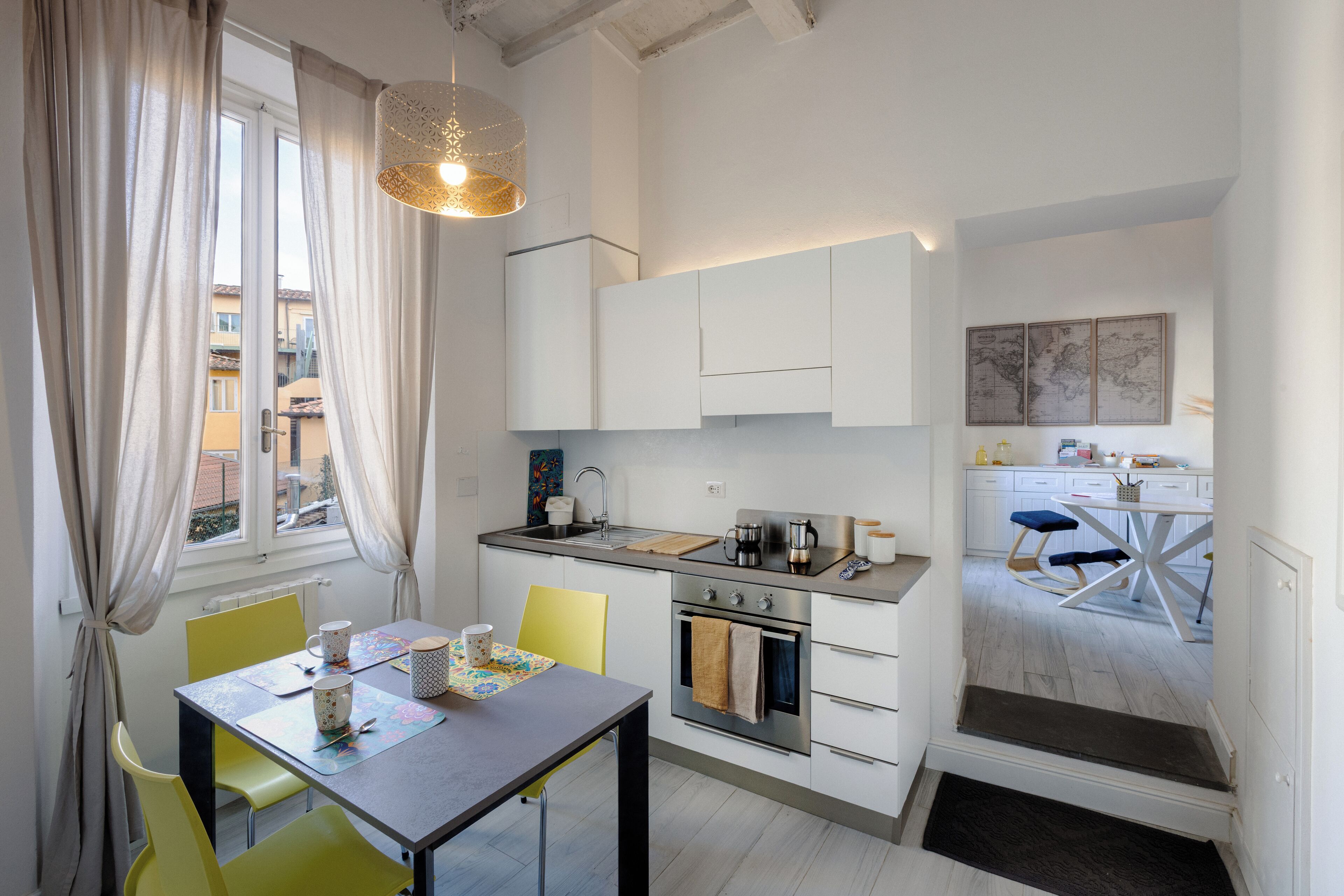 A compact kitchen with a dining area, a small oven, and a window with curtains.