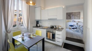 A compact kitchen with a dining area, a small oven, and a window with curtains. - Bright Apartment a few steps from Duomo and Train Station. Wifi, A/C, W&D  (Firenze)