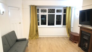 Ein Wohnzimmer mit grauem Sofa, Fernseher und Kamin.