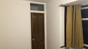 Ein Badezimmer mit Holztür, einem fenster mit Vorhang und weiß gefliesten Wänden.