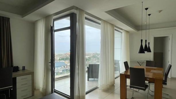 Una moderna camera d'albergo con balcone, zona pranzo e vista sulla città.