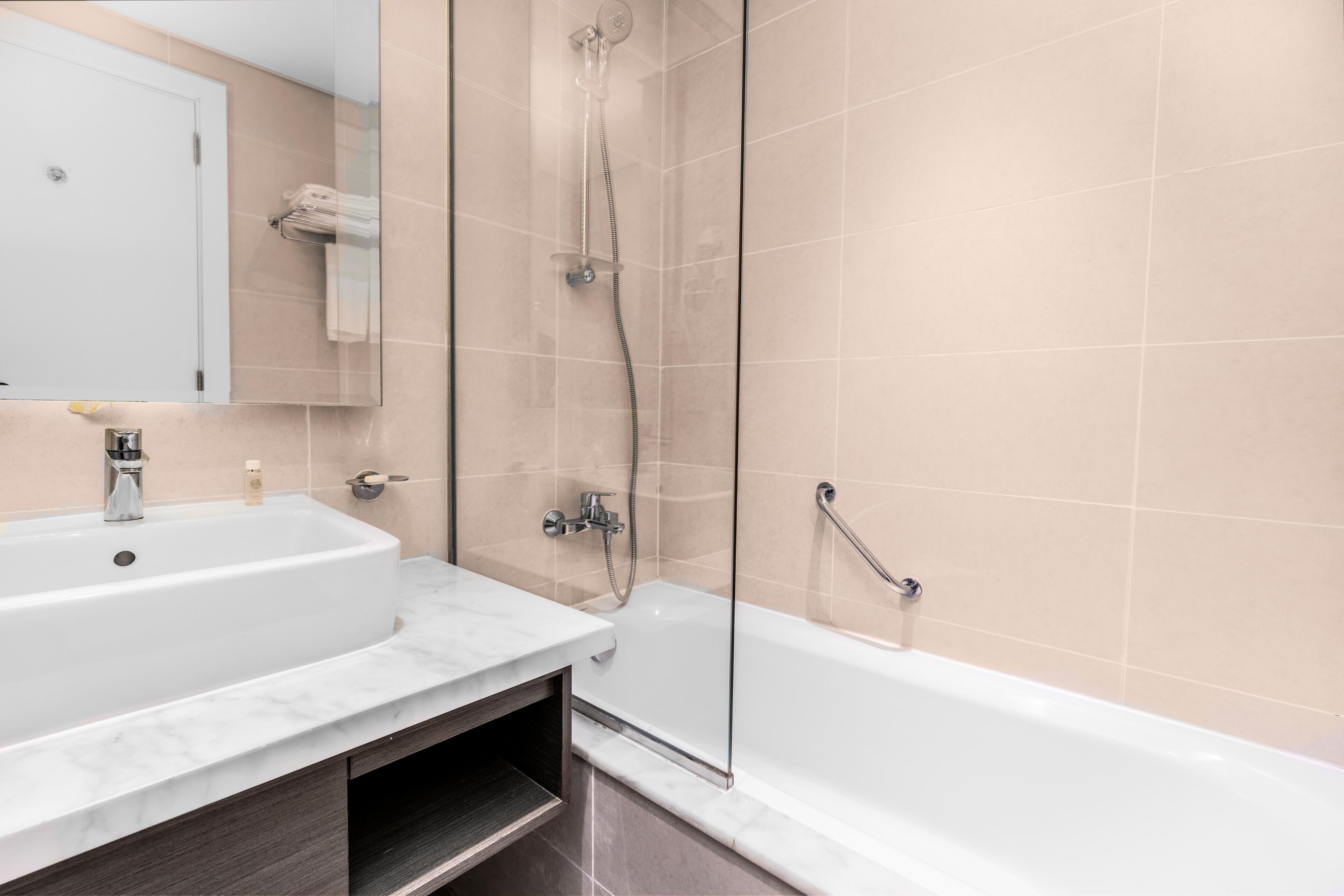 A modern bathroom with a white sink, a bathtub, and a glass-enclosed shower.