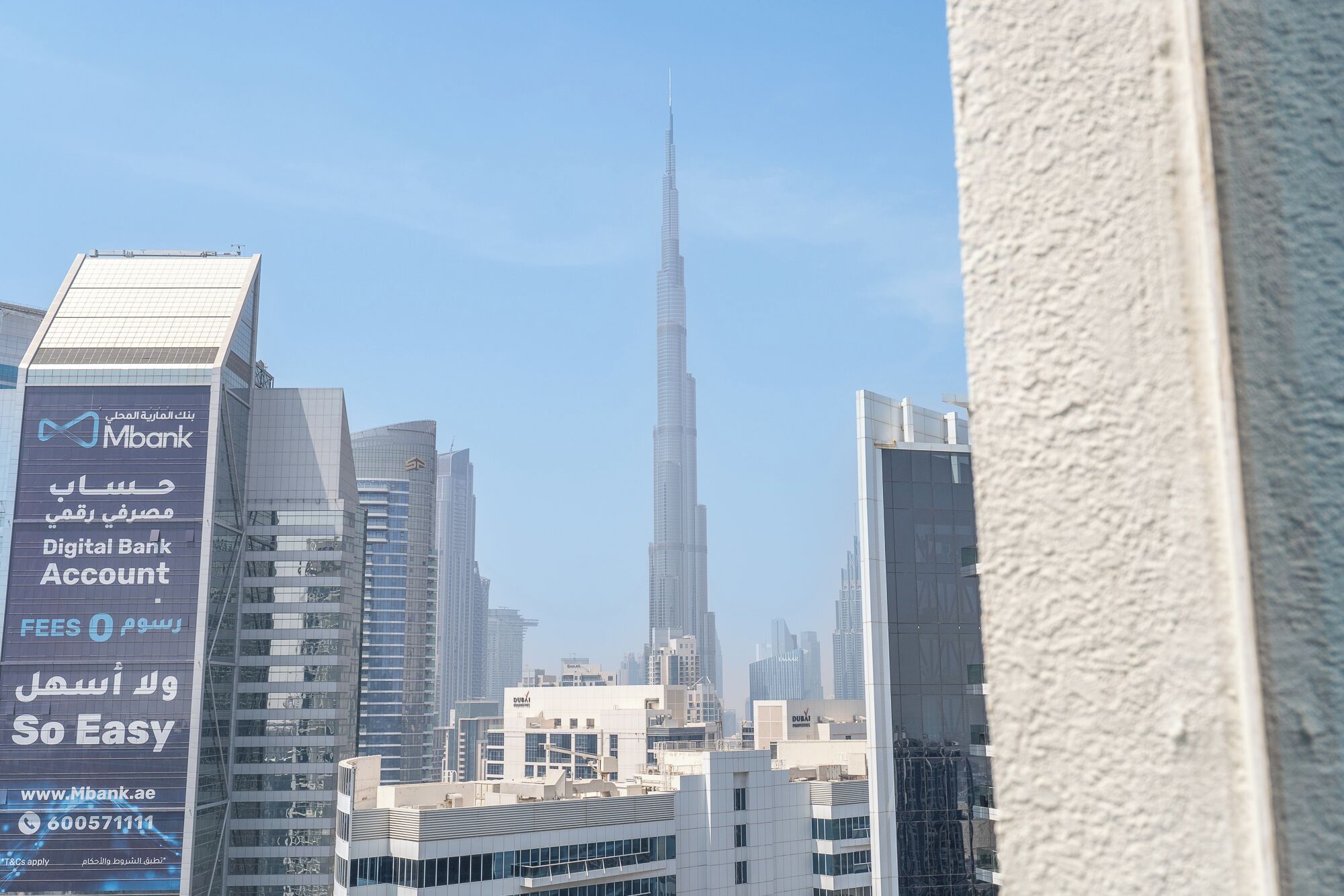 A cityscape with the Burj Khalifa in the background, surrounded by modern buildings with commercial signage.