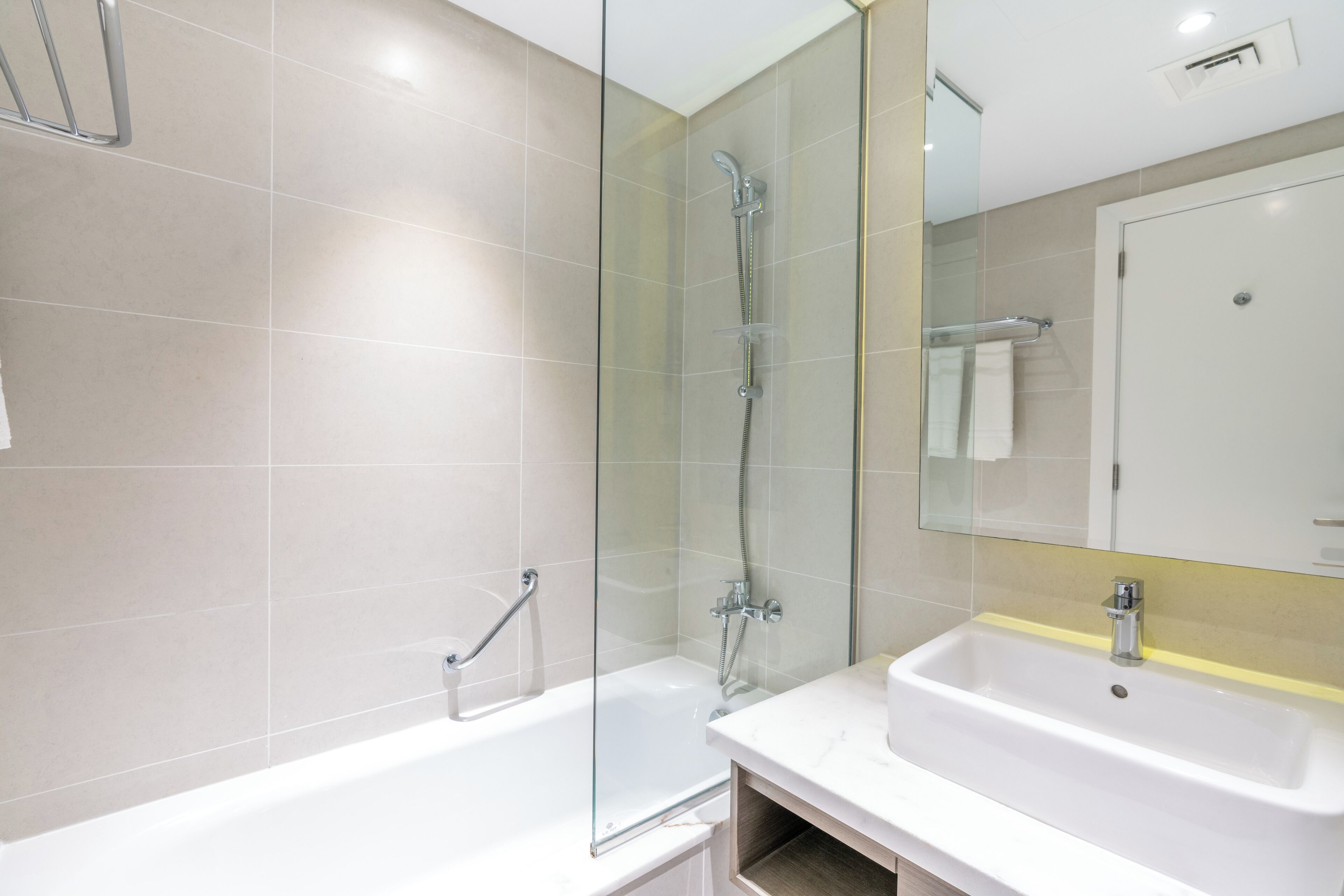 A modern bathroom with a glass-enclosed shower, a white sink, and a mirror above the sink.