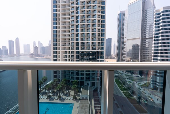 A high-rise building with a view of a city skyline and a swimming pool area.