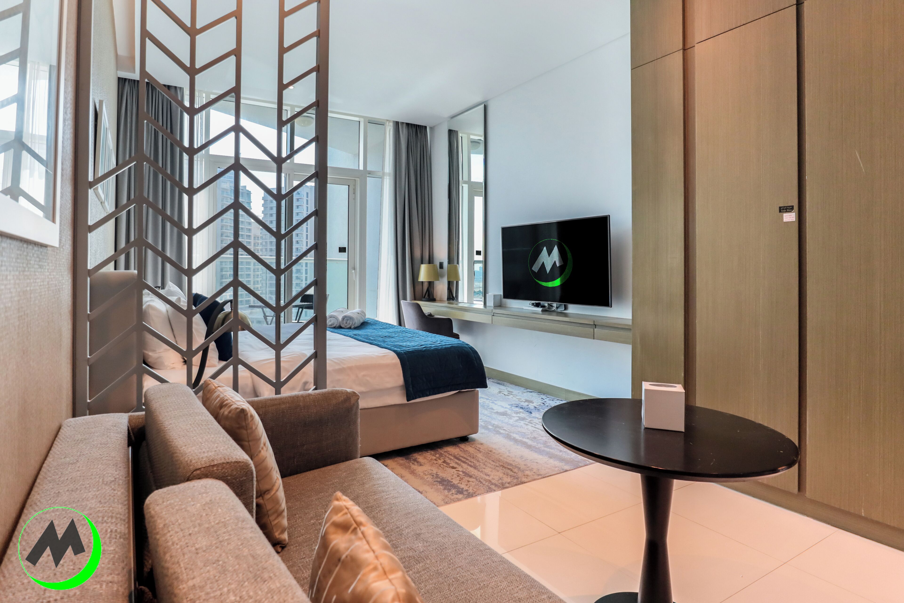 A modern hotel room with a sofa, a bed, a TV, and a small table.