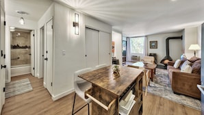 A spacious living area with a wooden dining table, a sofa, and a fireplace.