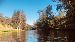 A river with trees on both sides and a person lying on a boat.