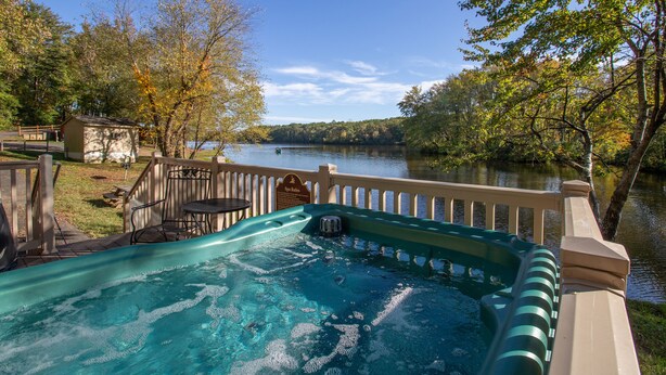 Un bain à remous avec une terrasse en bois et vue sur un lac.
