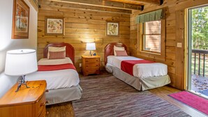 Une chambre rustique en bois avec deux lits, une table de chevet avec une lampe et une fenêtre donnant sur l’extérieur.