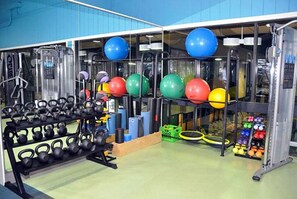 A gym with exercise equipment, including kettlebells, medicine balls, and a squat rack.