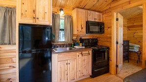Une cuisine compacte dotée d’armoires en bois, d’un réfrigérateur, d’une cuisinière, d’un four à micro-ondes et d’un évier.