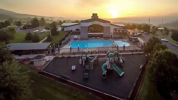 A hotel with a swimming pool, playground, and a large building with a distinctive arched entrance. - The Summit Two Bedroom Condo (Mc Gaheysville)