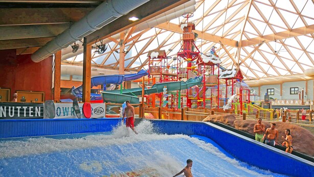 Parque acuático interior con toboganes y una piscina de olas.
