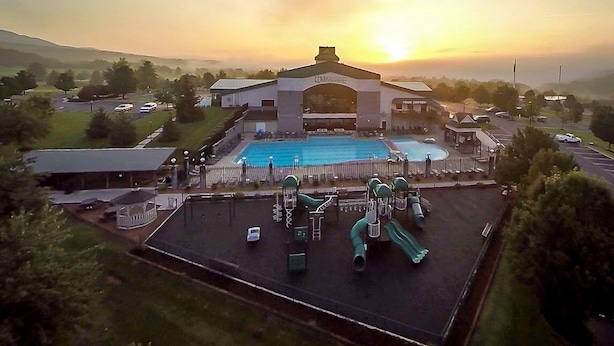 A hotel with a swimming pool, playground, and a large building with a distinctive arched entrance. - The Summit Premium Two Bedroom Condo (Mc Gaheysville)