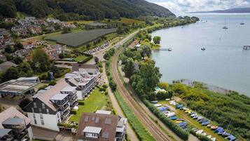 A lakeside town with residential buildings, a railway track, and a row of boats.