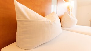 Een bed met witte kussens en een houten hoofdbord.