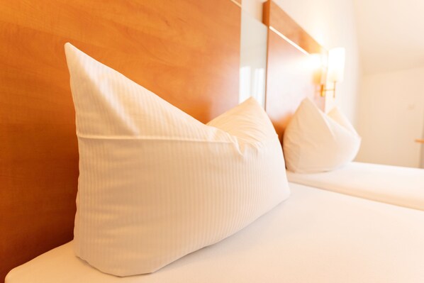 A bed with white pillows and a wooden headboard. - Hotel Rosmarin (Bodman-Ludwigshafen)