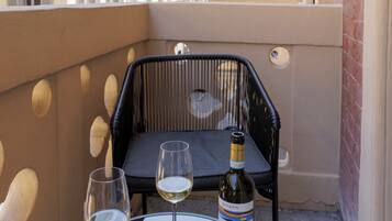 Ein Balkon mit Tisch, zwei Weingläsern und einer Weinflasche.