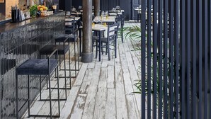 Interior de un restaurante con zona de bar, suelo de madera e iluminación moderna.