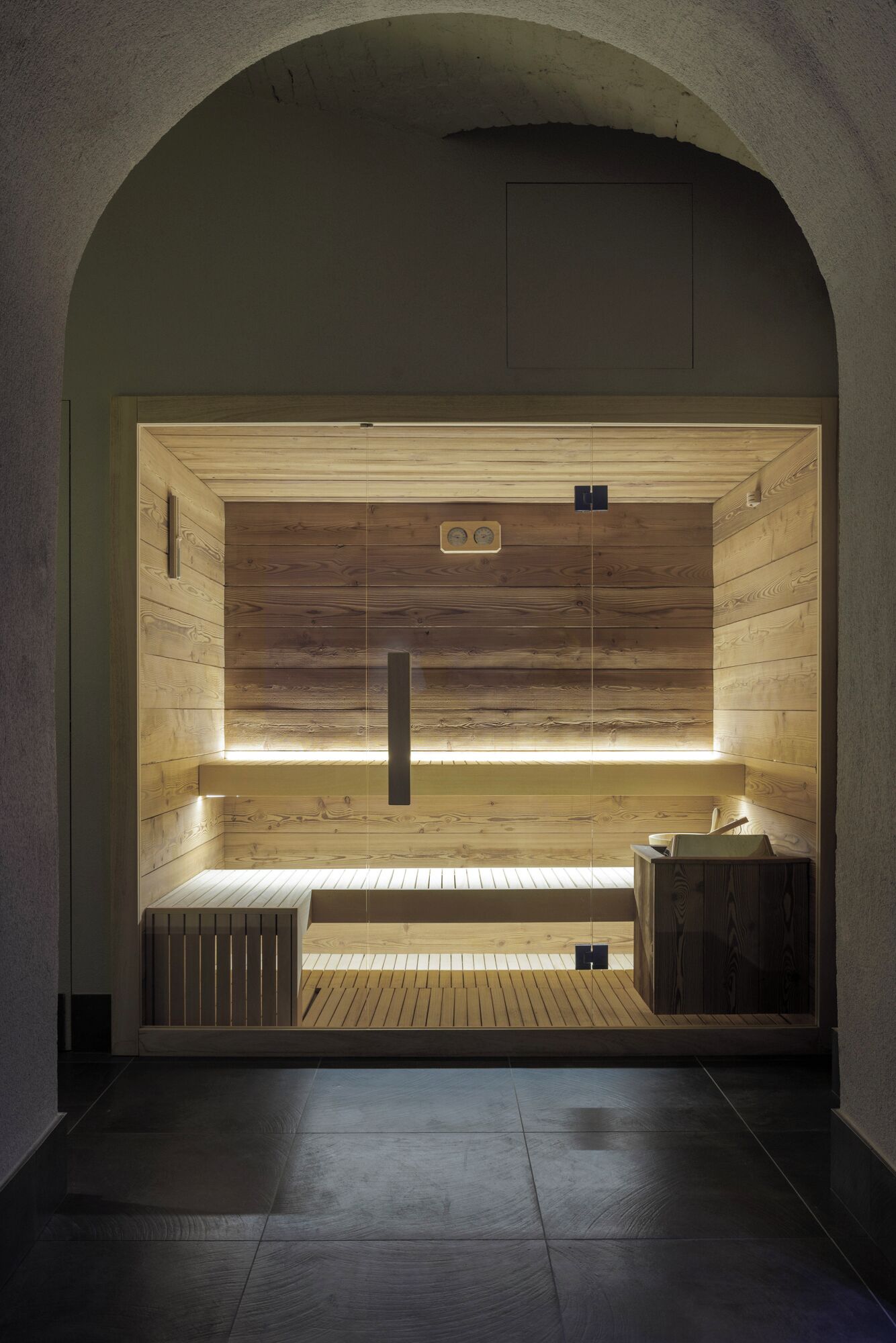 Un sauna aux murs en bois, doté d’un banc et d’un panneau de commande, ainsi que d’un autre banc muni d’une serviette.