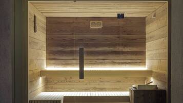 A sauna with wooden walls and a bench, featuring a control panel and a bench with a towel.