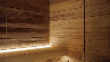 Una sauna in legno con soffitto inclinato, una panca di legno e un catino di legno con un pestello.