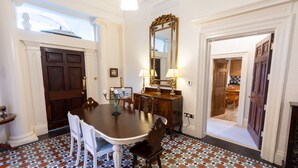A dining room with a large table, chairs, a chandelier, and a patterned floor.