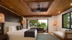 Une chambre moderne avec un grand lit, un canapé et une vue sur un jardin luxuriant.