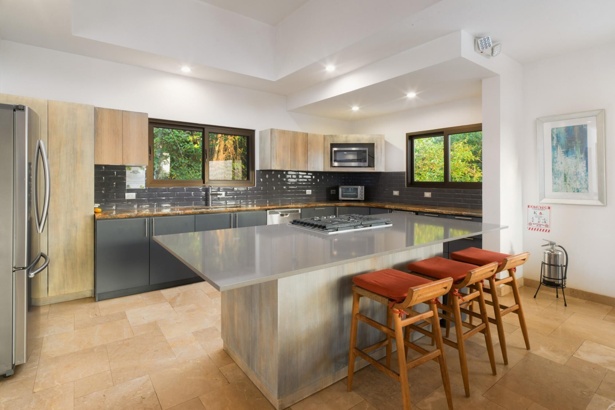 A modern kitchen with a large island, stainless steel appliances, and wooden cabinetry.