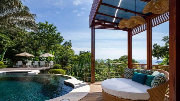 Un espace aménagé au bord de la piscine, avec un jacuzzi, des chaises longues et une vue sur l’océan.