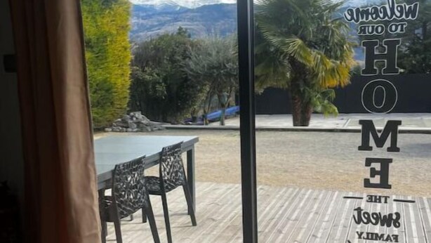 Een kamer met een schuifglazen deur naar een terras met een houten vloer, een stoel en een tafel.