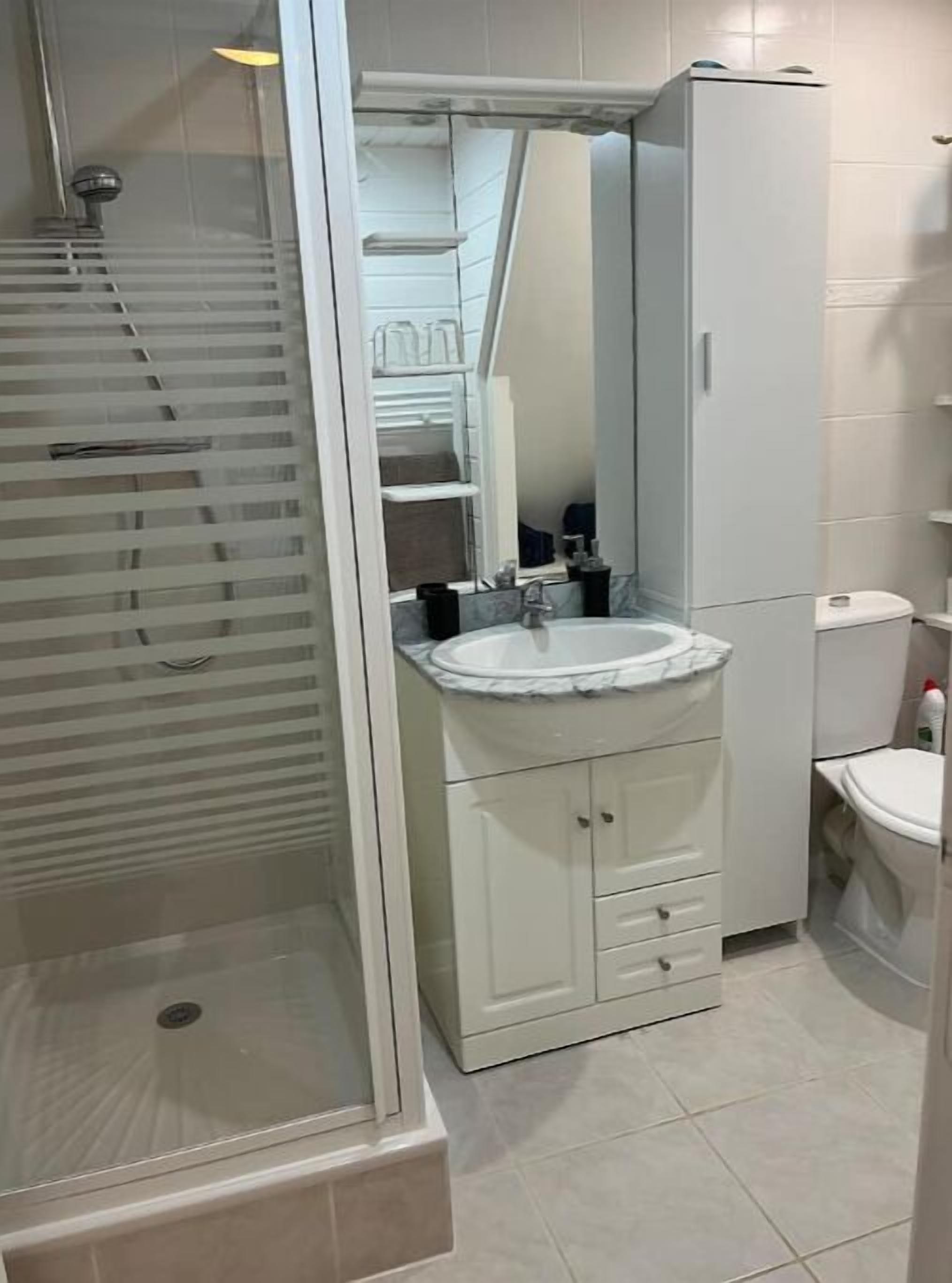 Un baño con ducha, lavabo, inodoro y espejo.
