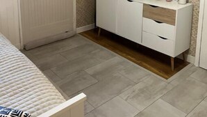 Een slaapkamer met een bed, een witte kledingkast, een spiegel en een hangplant.