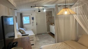 Een kleine hotelkamer met een bed, een bureau, een televisie en een raam.
