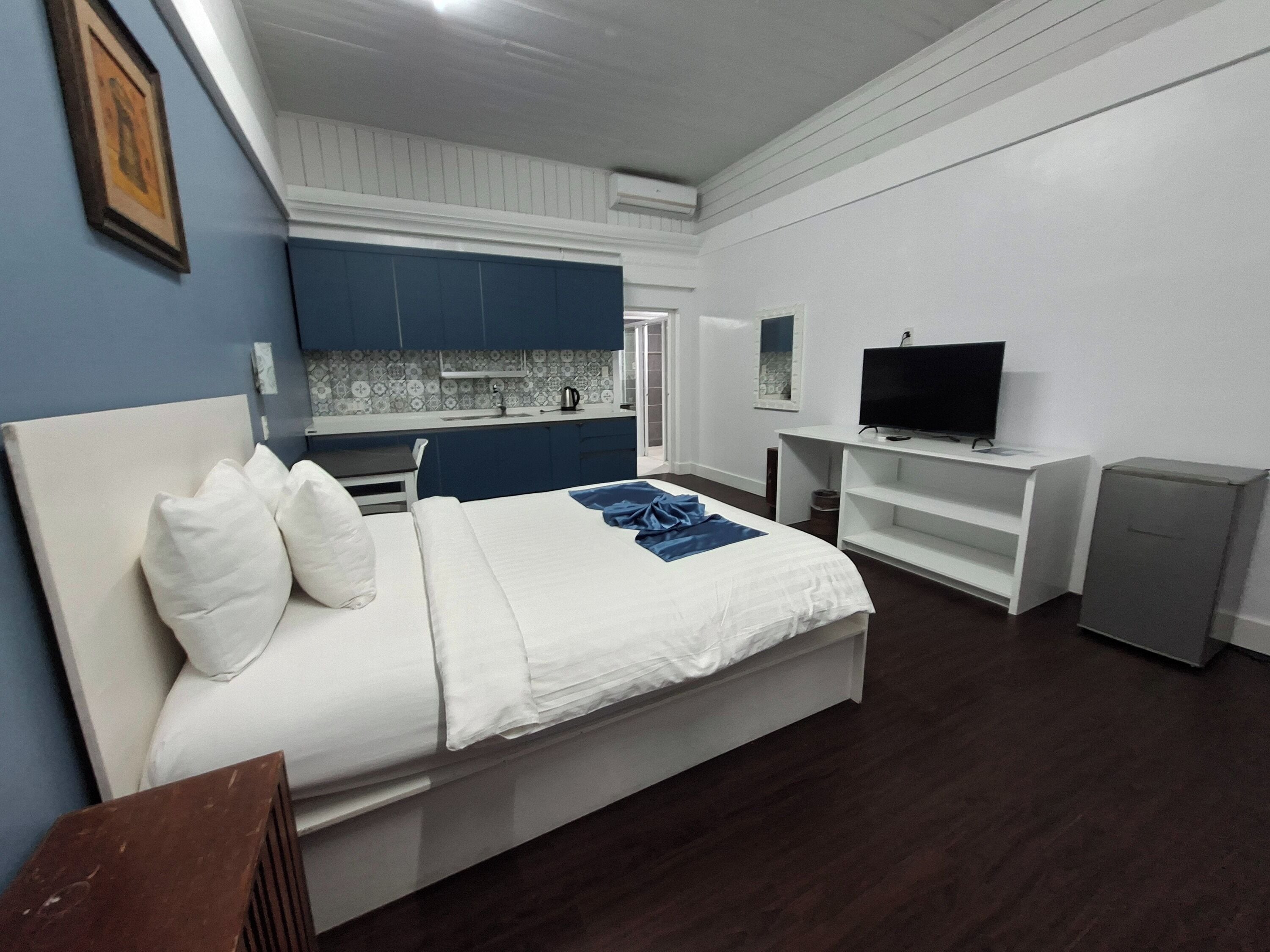 Une chambre avec un lit, une télévision, une petite kitchenette et une salle de bain.